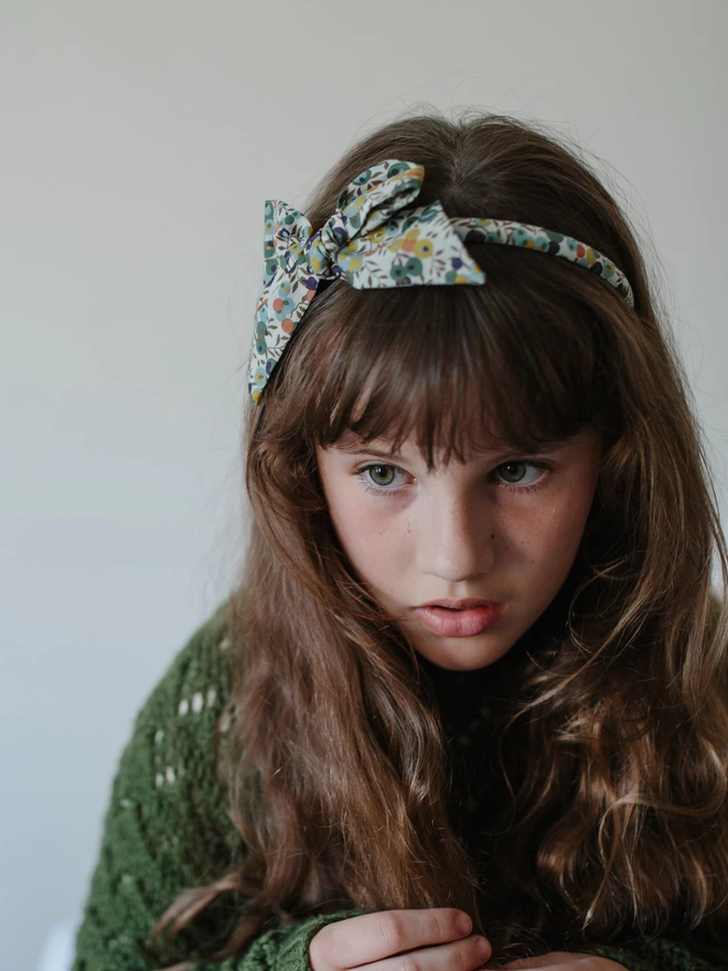 little girl with long brown hair and alice band in liberty