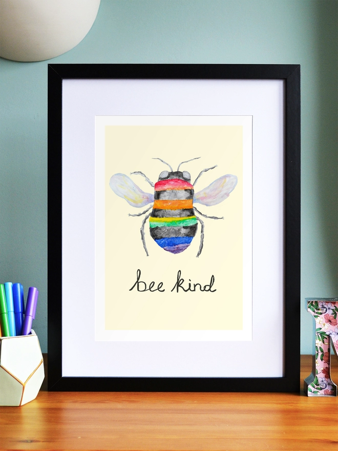 Art print saying 'Bee kind' in a black frame in a child's room