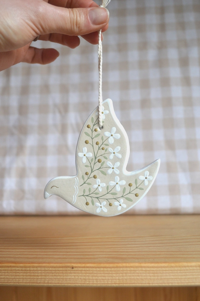 beige ceramic hanging bird ornament with white floral design