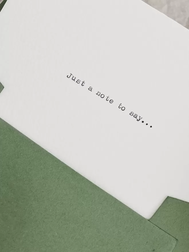 notecard with green envelope and the text 'just a note to say' typed on the cover