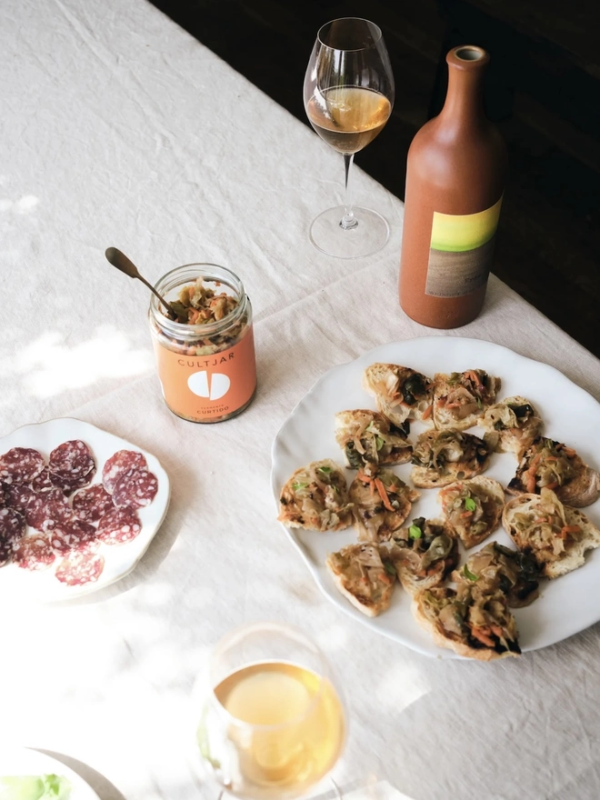 Ferment Intro Journey (Set Of 5), a jar of ferment sitting on a dining table. It is accompanied by other foods and drinks on a white surface. 