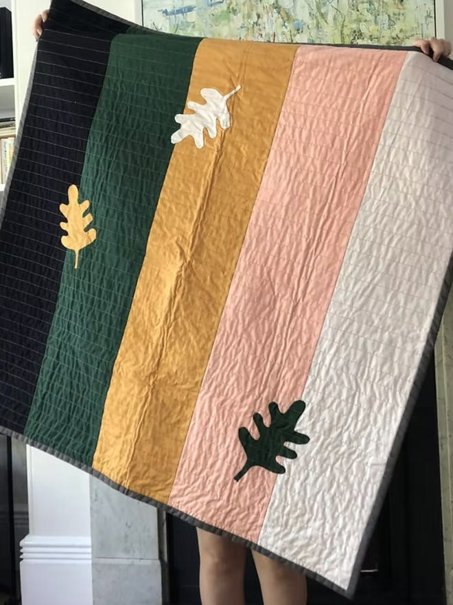 Autumn Leaf Stripe Cotton Baby Quilt/ Mat. A multicoloured leaf design baby sized quilt to use as a baby mat or in the nursery.
