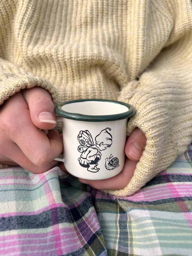 a mini enamel mug featuring an etching of a pixie fairy boy meeting a snail
