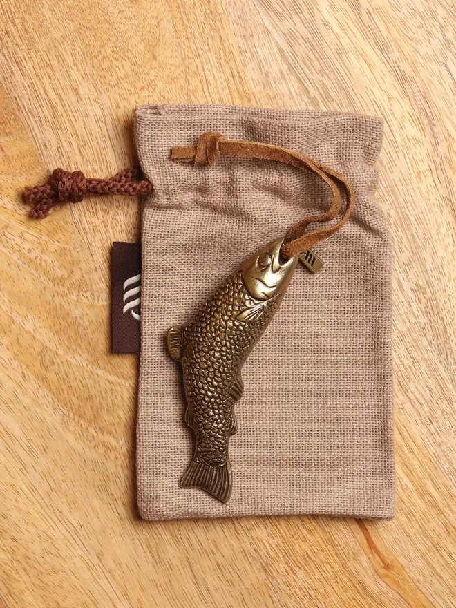Metal fish hanging decoration on linen gift bag