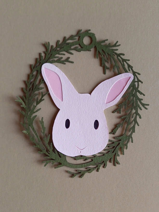 Black Bunny Easter Tree Decoration. White bunny face with black eyes and pale pink ears inside olive green foliage wreath oval