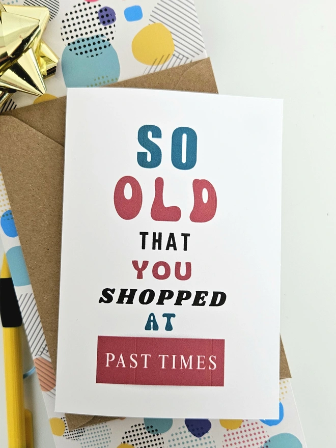 A photograph of the front of a humorous A6 greeting card illustrated using brightly coloured text and the retro shop logo. The text says so old you shopped at Past Times.