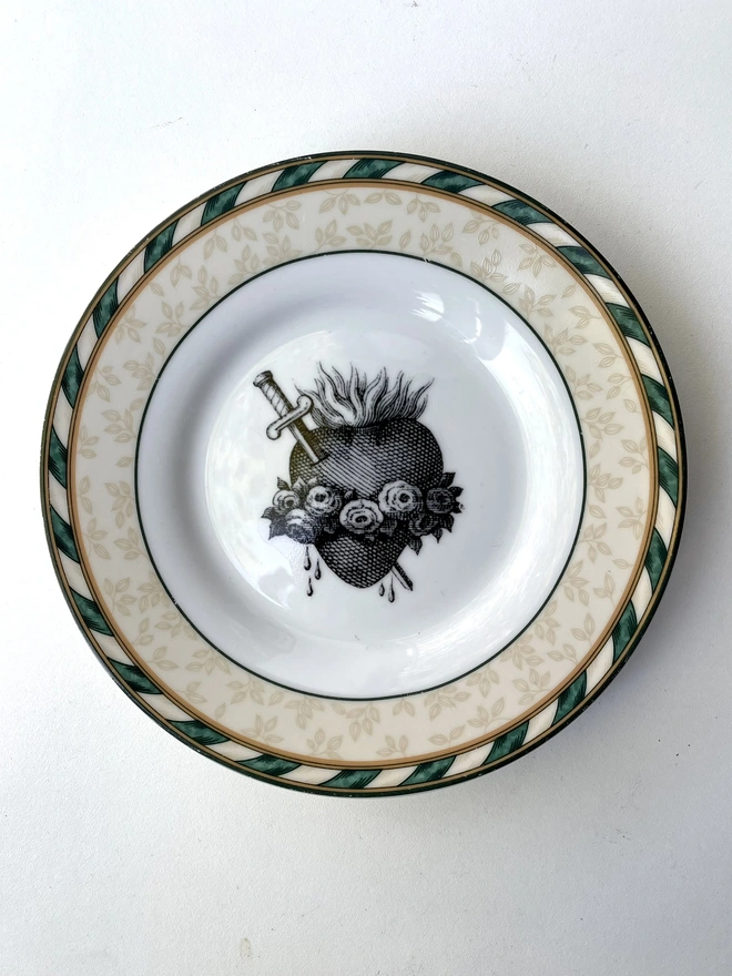 a vintage plate with an ornate border and in the centre is an old illustration of a beautiful sacred heart