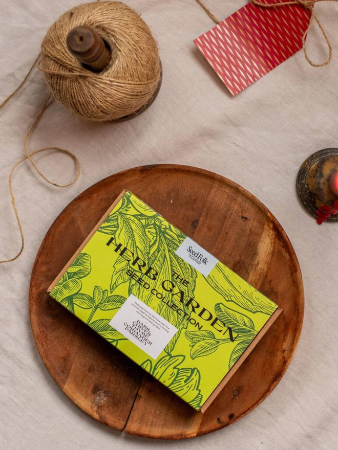the herb garden seed collection. packaging for seed packets decorated with illustrated green leaf outlines. box photographed in wooden bowl on counter.