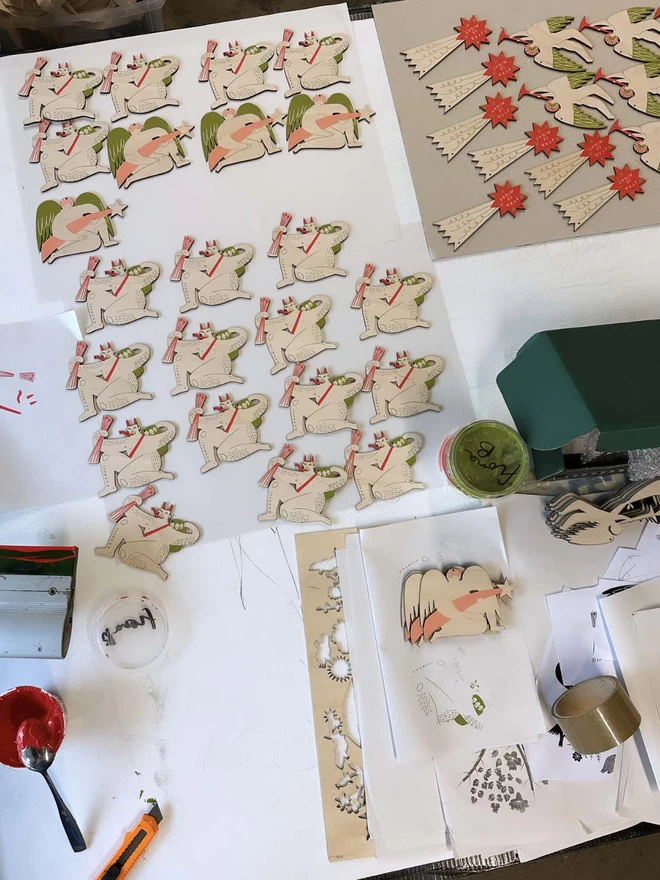 Wooden decorations are laid out, in different stages of being screen printed