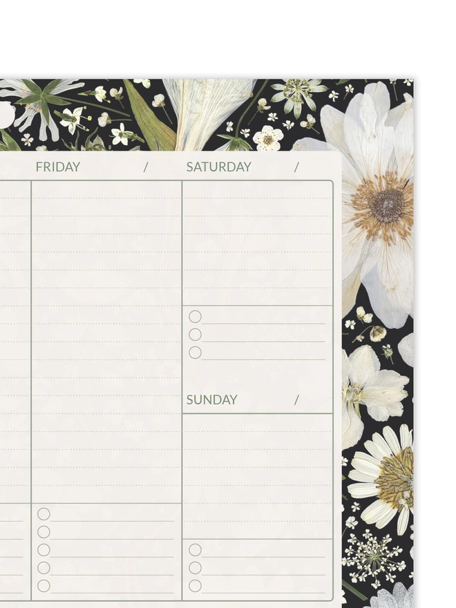 Close detail of Weekly planner desk pad with elegant pressed white flowers on black background, perfect for task organisation at work or home; suitable for office professionals, parents, and creative planners.