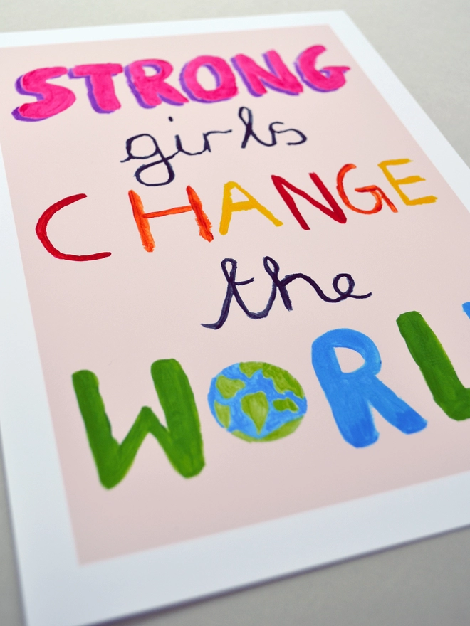 Close up of an art print saying 'Strong girls change the world'
