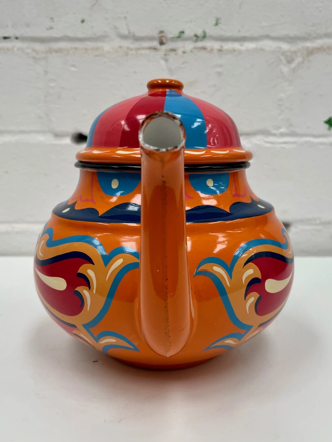 Orange vintage teapot with hinged lid, hand painted with a traditional fairground inspired design in pink, red, yellow and blue.