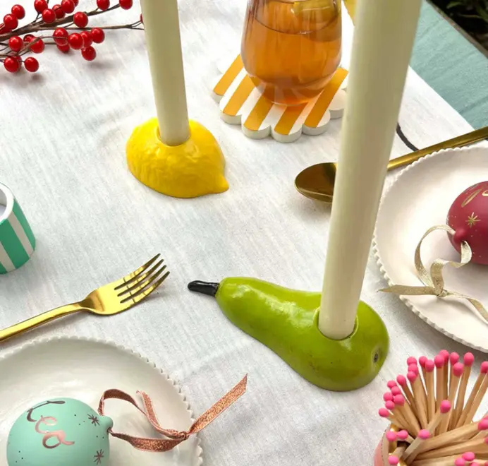 Pear Candlestick Holder. Candle placed in green pear candlestick holders displayed on a table alongside matchstick holder. 