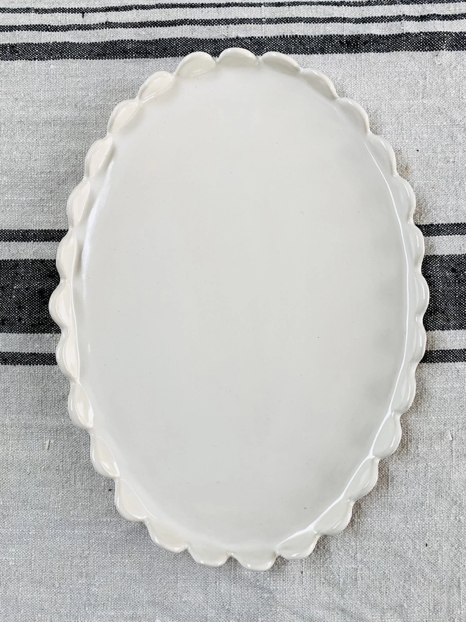 top view of white scallloped edge oval cake plate 