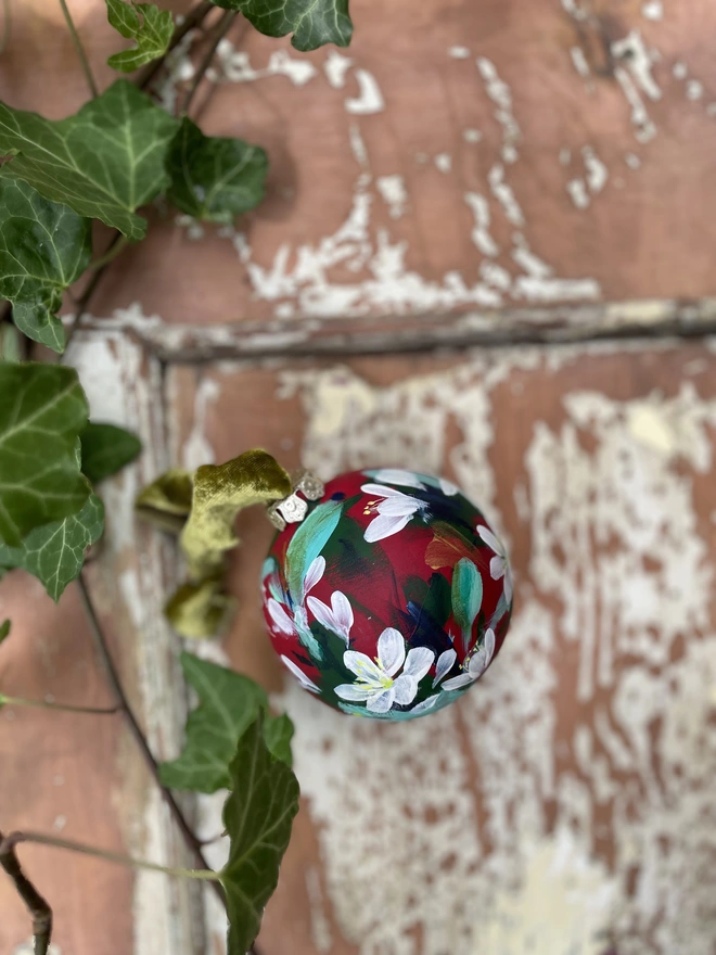 Hand painted floral ceramic bauble paperwhite flowers on a rich red background 