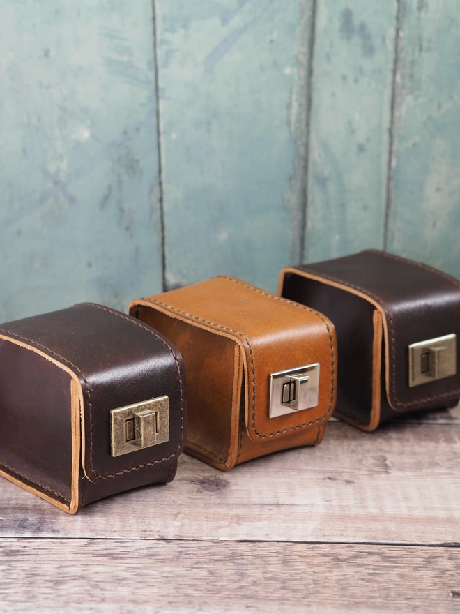 Personalised leather watch cases. A row of 3 handmade leather watch cases with chunky clasps. Alternating in colour between dark brown and tan brown.