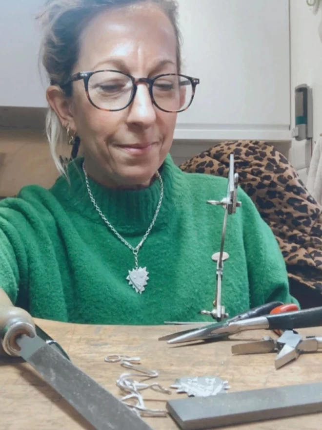 Laura at the bench making jagged and wearing a silver one