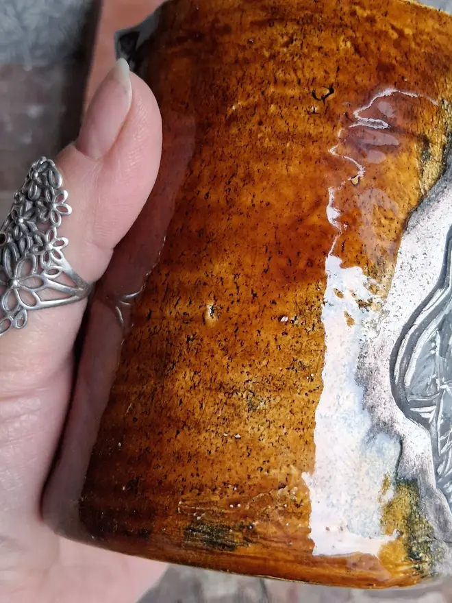 linocut owl ceramic mug.  a brown mug bearing an owl design photographed from the side.