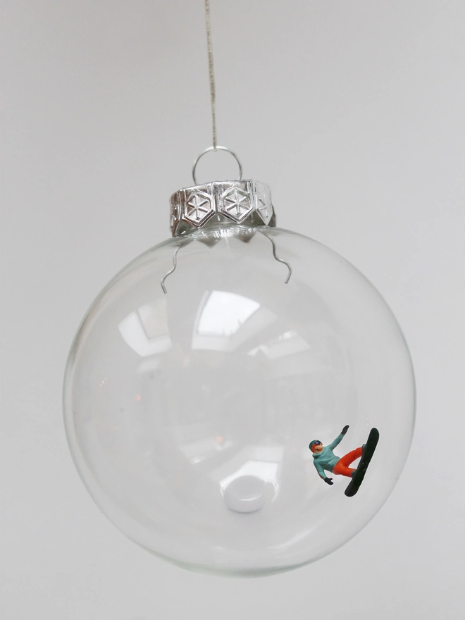 Miniature figure of a male snowboarder in a glass hanging christmas bauble 