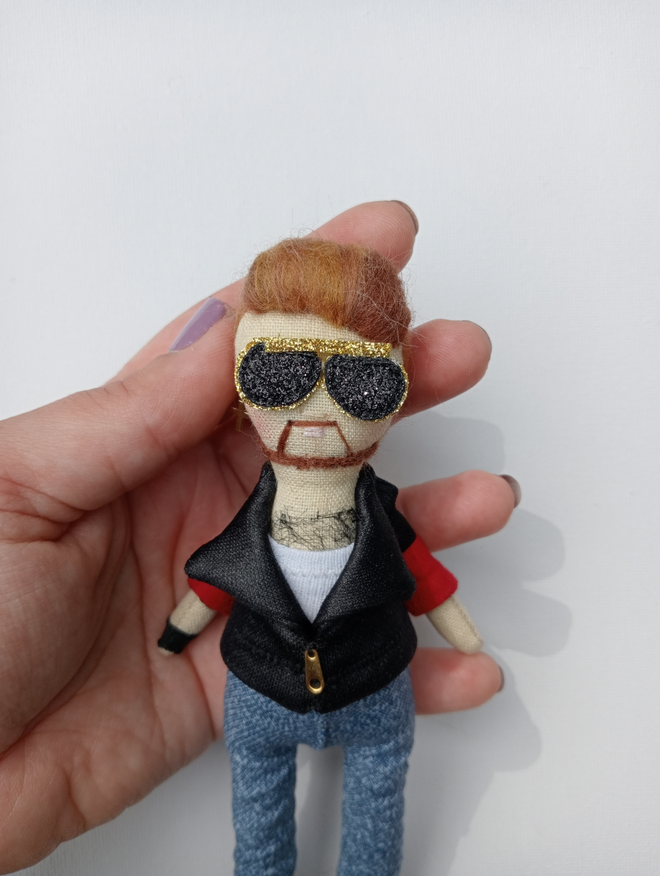 George Michael mini decorative icon doll held in a left hand for scale against a white background 