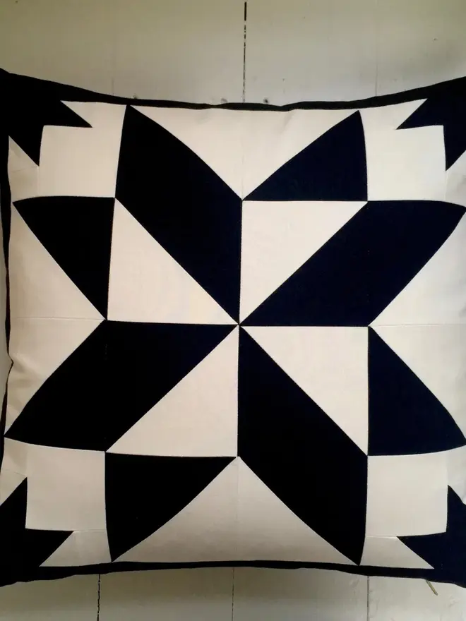 Celest At Night Patchwork Cushion, against a wooden board. 