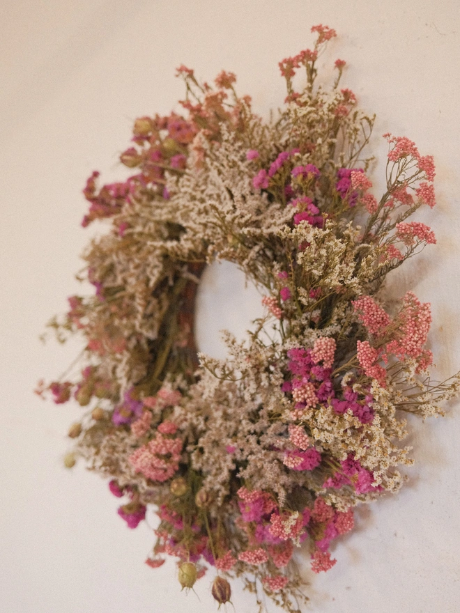 brown and pink dried flower wreath hanging on wall