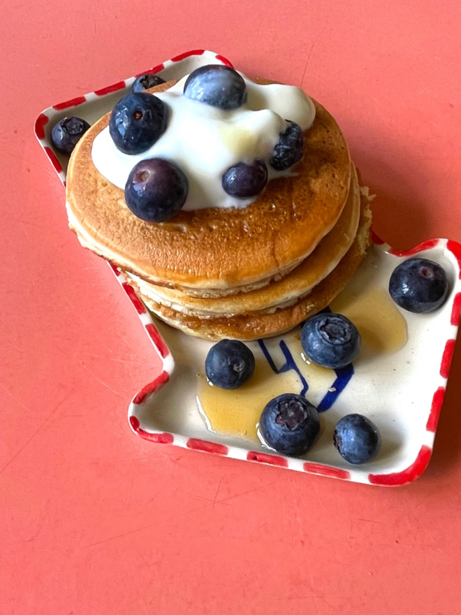 Eat Dish. A dish shaped as an arrow with pancakes on top.
