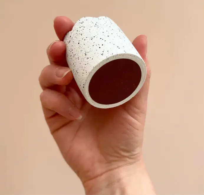 Striker Disc held in a hand against a beige background. 