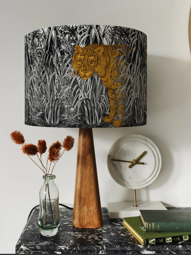 A decorative lampshade featuring an elegant tiger moving through tall tropical grasses, inspired by Henri Rousseau’s jungle paintings, with a rich botanical design.