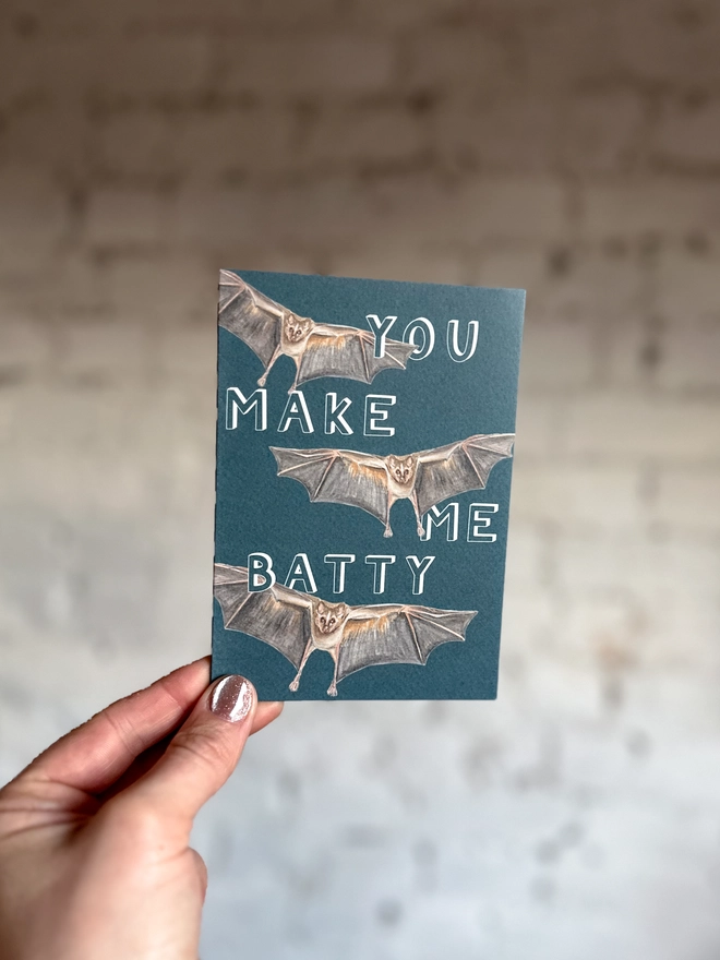 deep blue card featuring a realistic illustration of three bats and the text "You Make Me Batty"