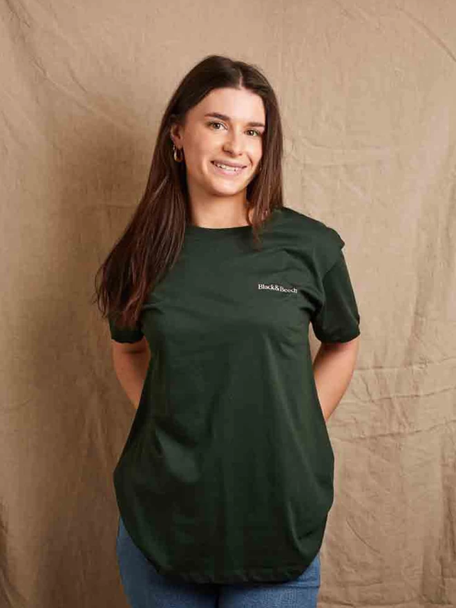 Model is showing the front of the forest green feminist icon t-shirt. Our companies name - Black & Beech is printed in pale pink on the left chest 