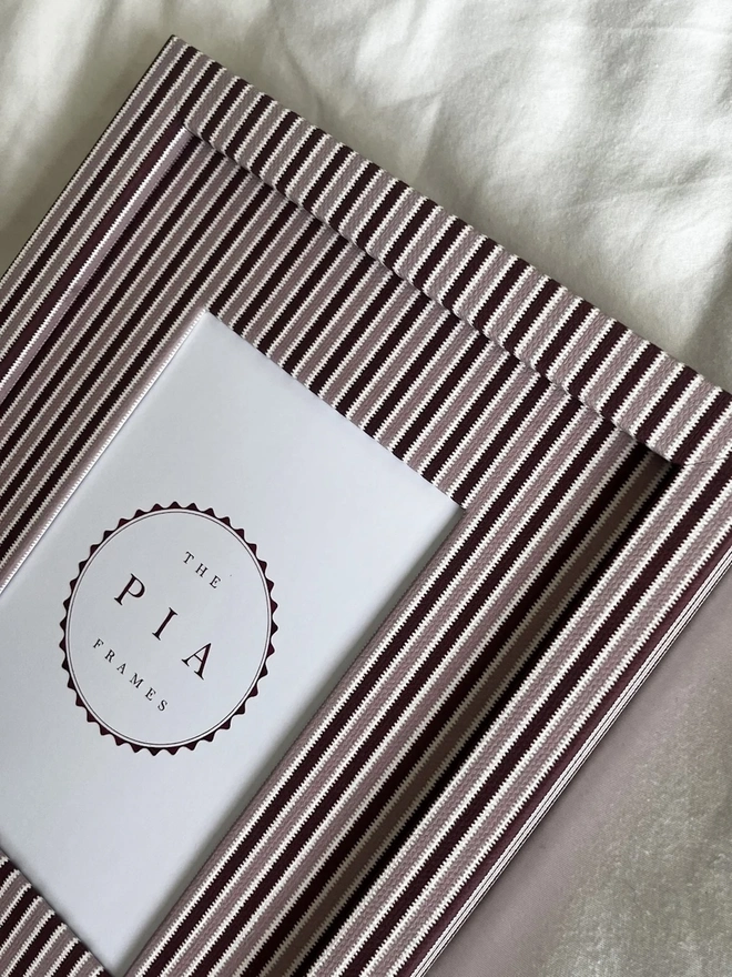Blush & Burgundy Zigzag Frame, a colourful striped frame sitting on a plain white surface. 