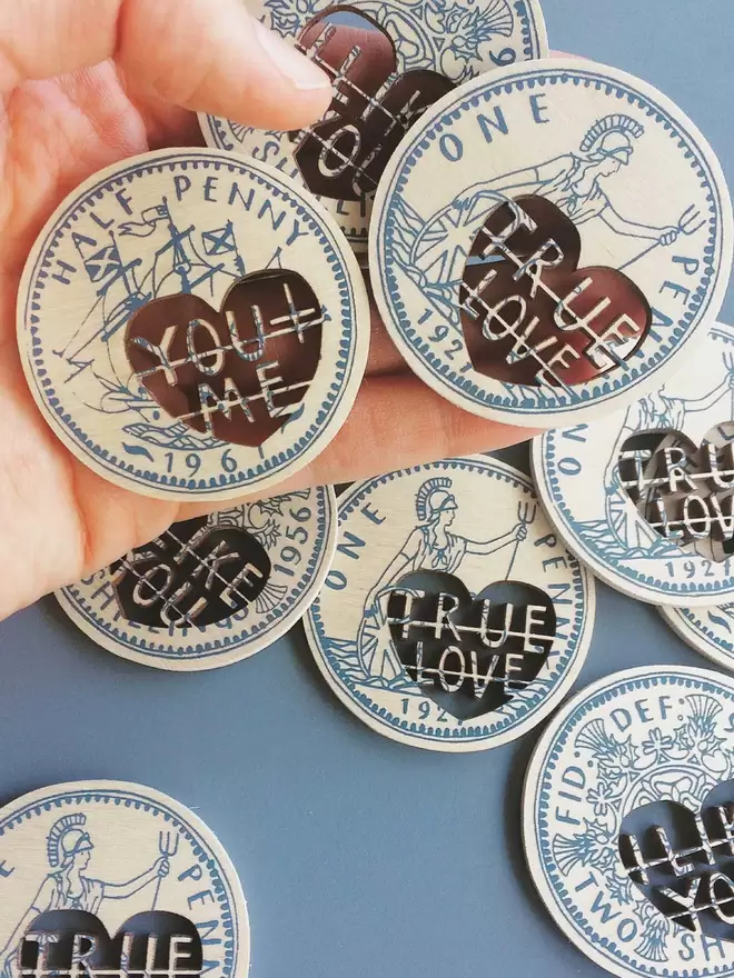 Blue screenprinted love tokens, the designs are based on old coins and have laser cut messages on.