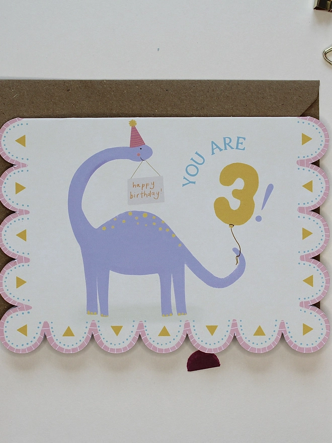 illustrated dinosaur birthday card. scallop edged card illustrated with stegosaurus.