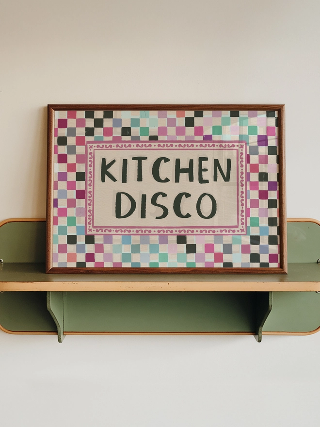 checkerboard pattern print in disco ball colours with text ' kitchen disco' written in the centre