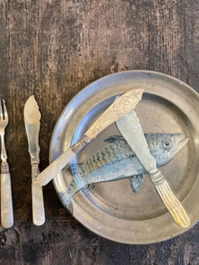 Oil Painted Fish Knife & Mackerel On Antique Pewter Plate, on a wooden table next to silver crockery.  