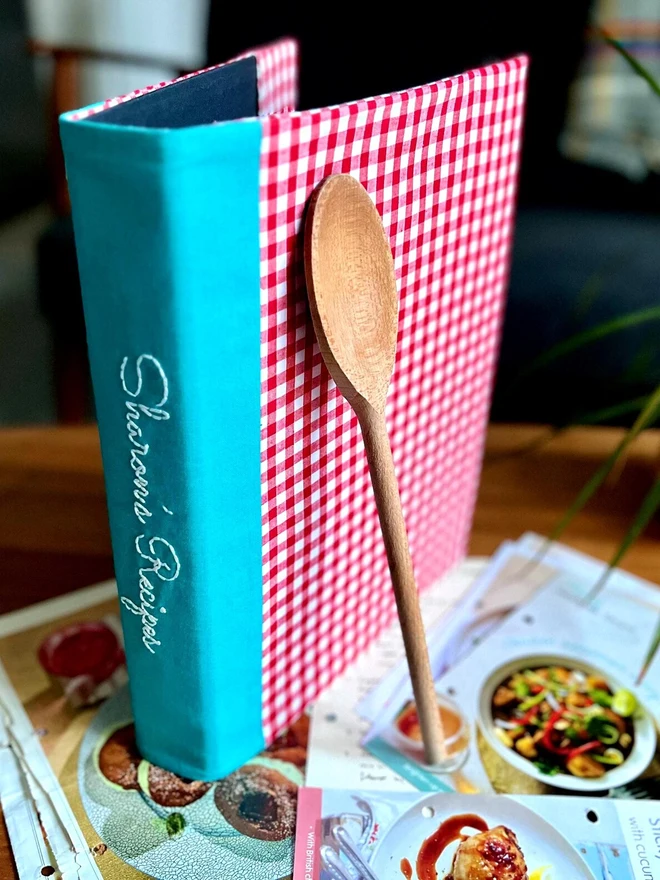 Ring binder with red and white gingham cover. Personalisation embroidered on the teal spine