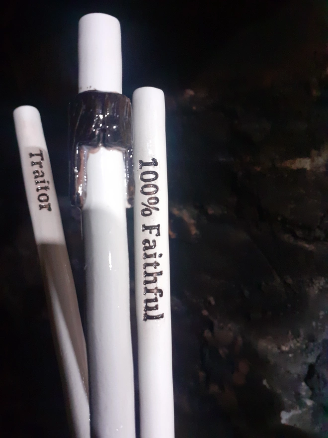 Three reusable ceramic straws laid side by side, including “Traitor” and “100% Faithful” text straws and a central straw with a dark fringe design, handmade in Wales.