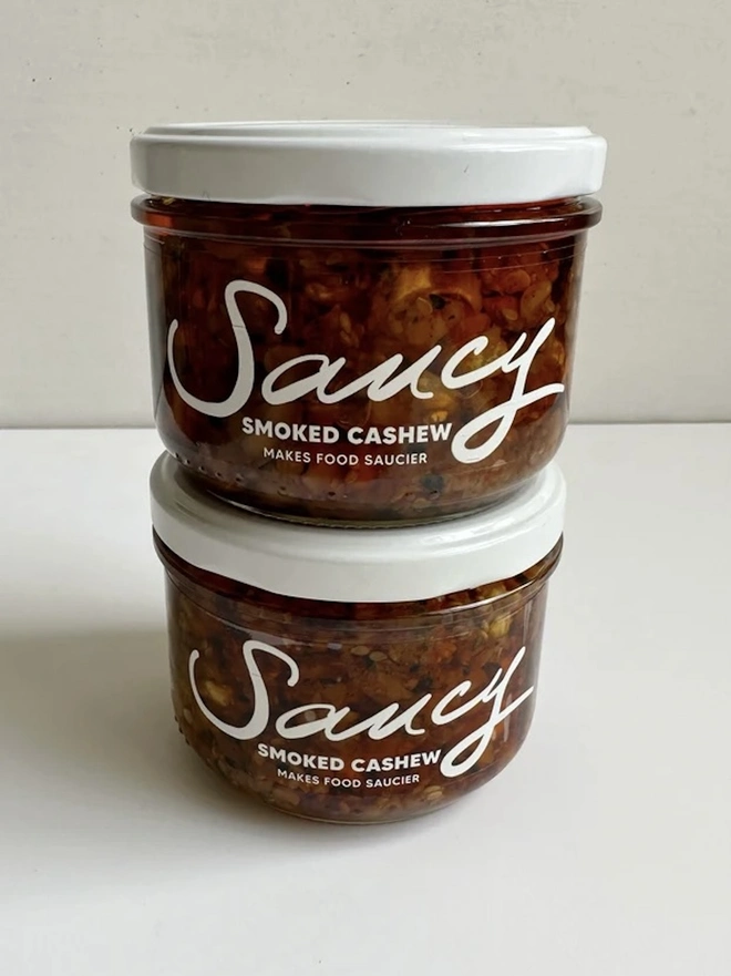 Smoked Cashew (Set Of 2), a pair of smoked cashew sauces sitting on a white table in front of a grey backdrop. 
