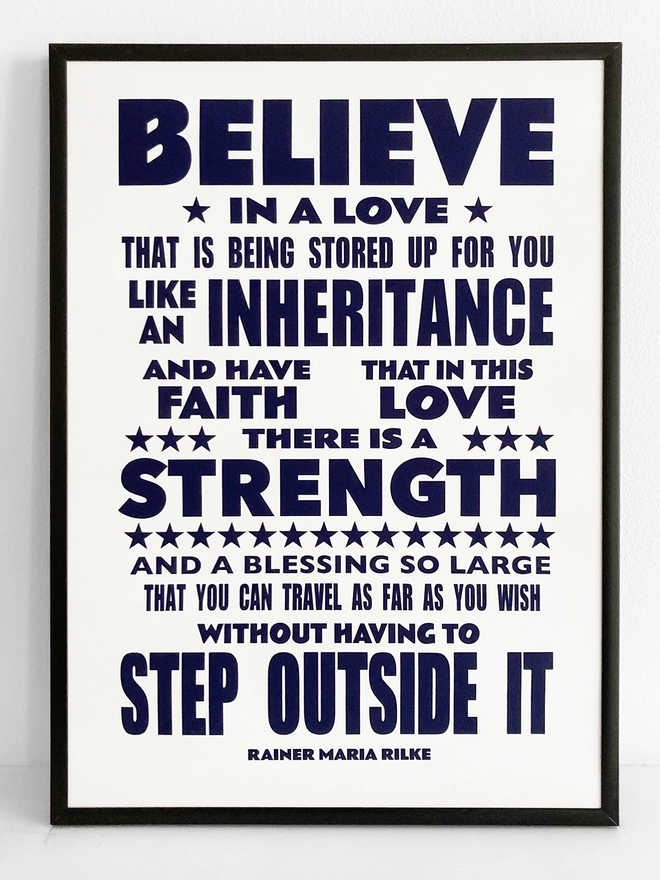 Framed typographic print with text by Rainer Maria Rilke. The quote reads “Believe in love that is stored up for you like an inheritance and have faith that in this love there is a strength and a blessing so large that you can travel as far as you wish without having to step outside it”  Blue text on a white background.