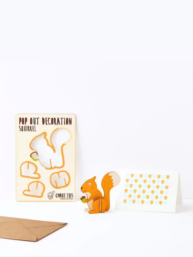 Ginger squirrel decoration and acorn pattern greeting card and brown kraft envelope on a white background