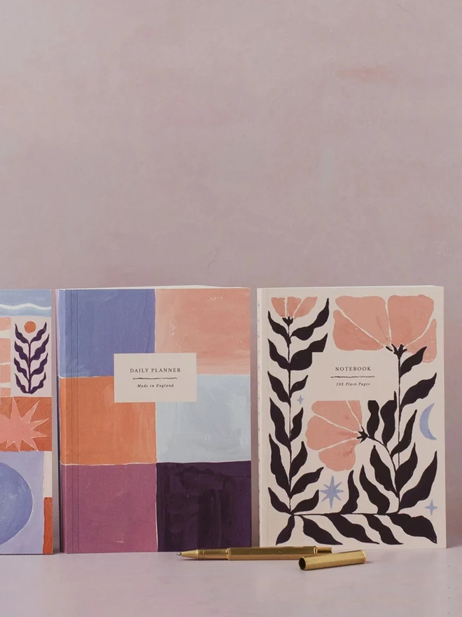 Botanical Notebook beside a colourful checked notebook