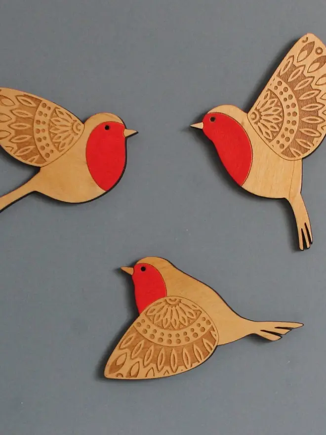 Folk Art Wooden Wall Robins (Set Of 3), a group of wooden robins flying hung up on a wall. 