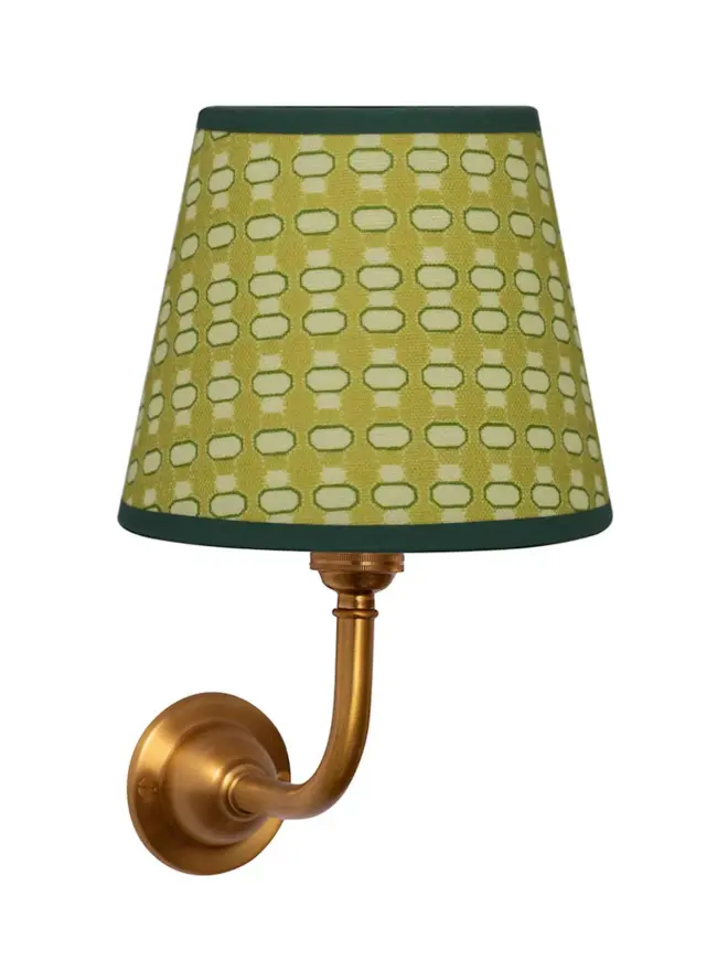 green lalli patterned lampshade on golden sconce, on white background