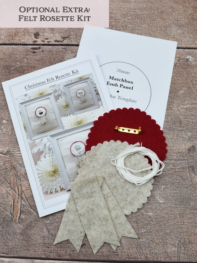 The rosette kit contents, showing instruction sheet, pattern piece, red & beige felt pieces, white yarn & gilt brooch.