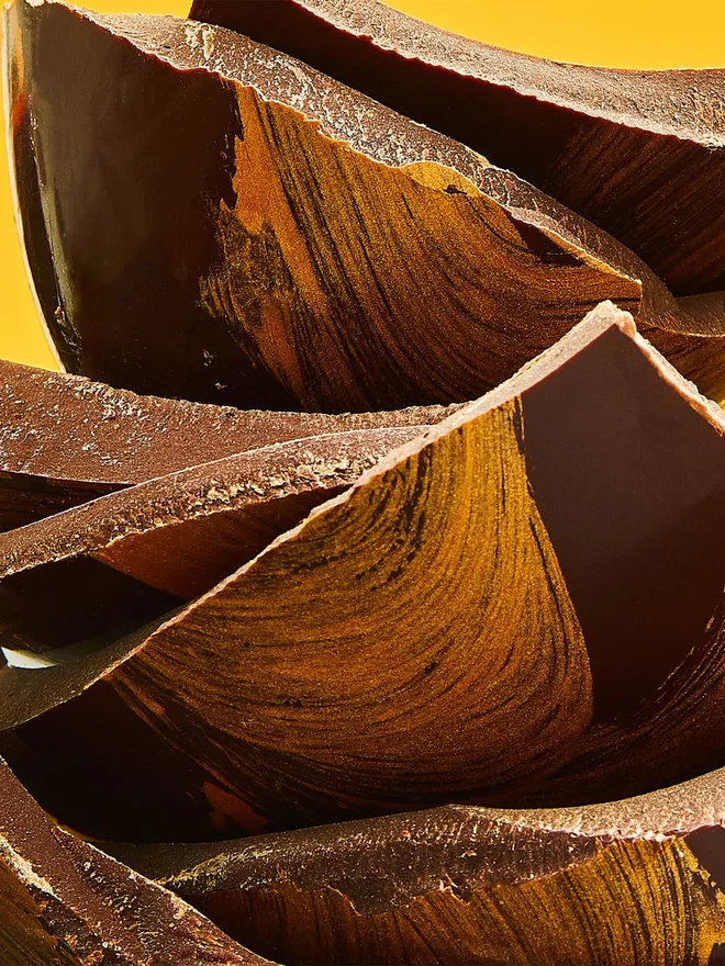 A stack of dark chocolate Easter egg pieces decorated with gold cocoa butter