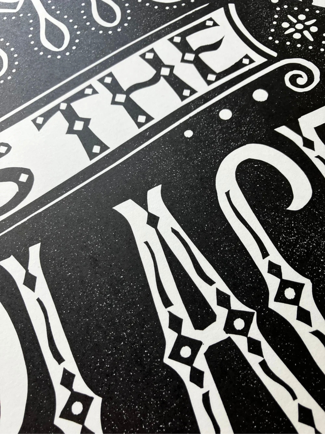 this is the place linocut. a linocut phrase printed with black paint.