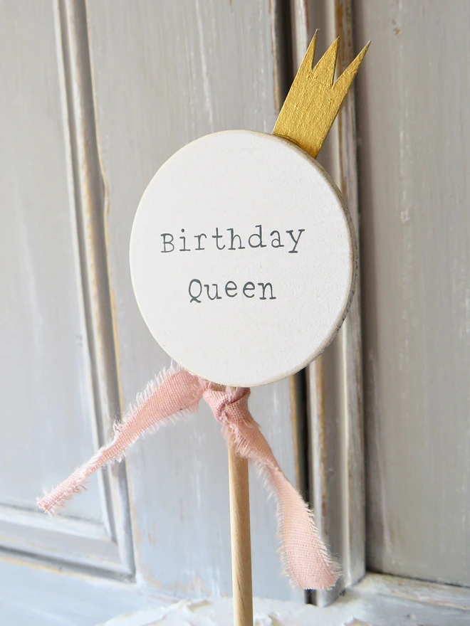 wooden circle shaped cake topper with hand painted message, gold painted crown detail and custom ribbon