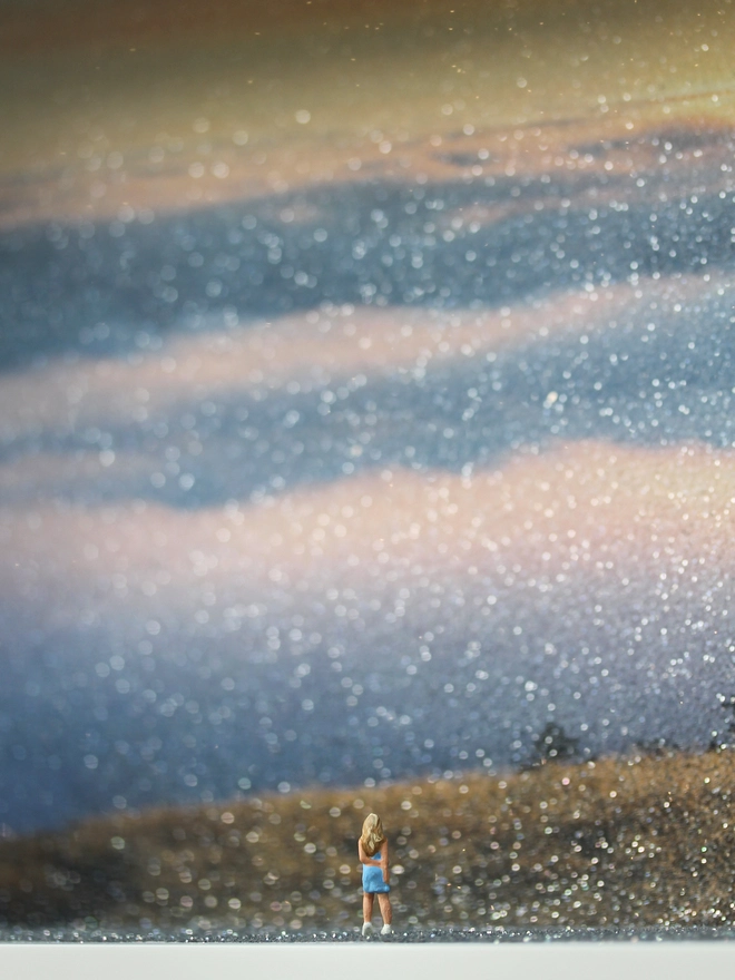 TIny figure of a young woman looking out from a hill overlooking the beautiful sunset through clouds (close up)