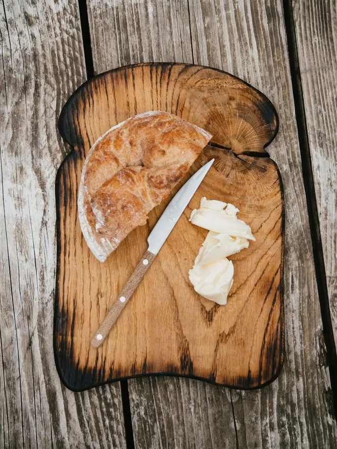 ‘Toast Of The Town’ Large Oak Bread Board  seen on a wooden table with bread and butter on top.